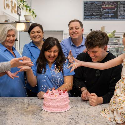 Employees sprinkling a cake.