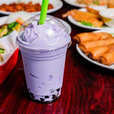 Taro boba milk tea in a clear plastic cup with a lid.