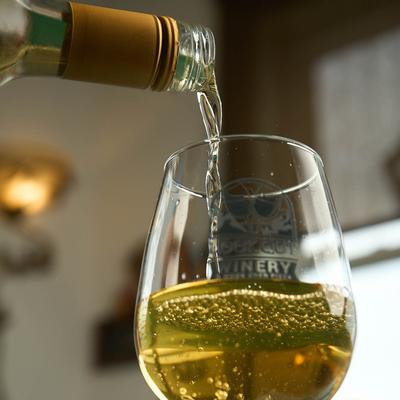White wine being poured into a glass, close up, low angle.