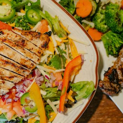 Southwest chicken salad served alongside grilled steak, close-up.