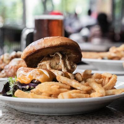 Chesapeake burger with fries, food and drinks in the background.