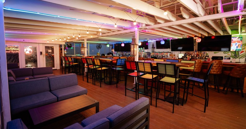 Interior, bar with stools, high tables with colorful bar stools, two-seater sofas with tables