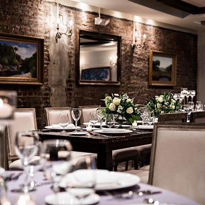 Elegantly set tables surrounded by brick walls and framed paintings.