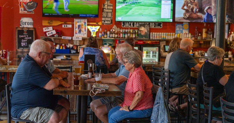 Interior, bar area, tables, people, bar, tv's above