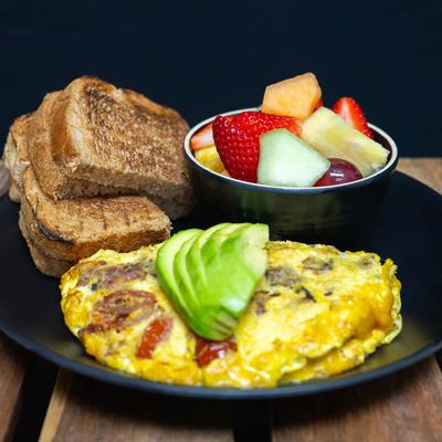 Bacon Avocado Tomato Omelet with a Fresh Fruit Salad and toast.