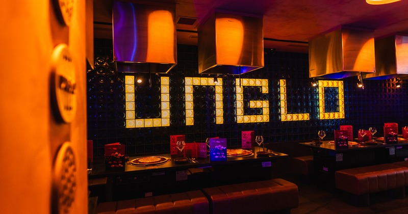 Interior of dining area, tables equipped with built in hot pot burners, restaurant logo on the wall