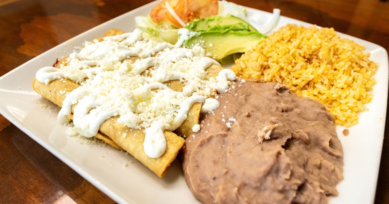 Flautas with sour cream, cheese, lettuce, tomato, avocado, rice, and refried beans