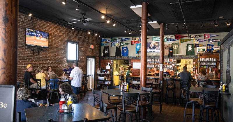 Interior, tables with seated guests, guests at the bar, sports decor, TV