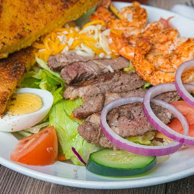 Steak and Shrimp Salad, with lettuce, tomato, cucumber, cheese, onion, egg, and garlic toast.