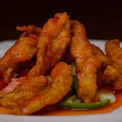 Deep fried seafood dish in a red sauce, served over sliced vegetables.