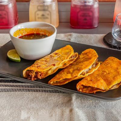 Birria tacos served with dipping broth.