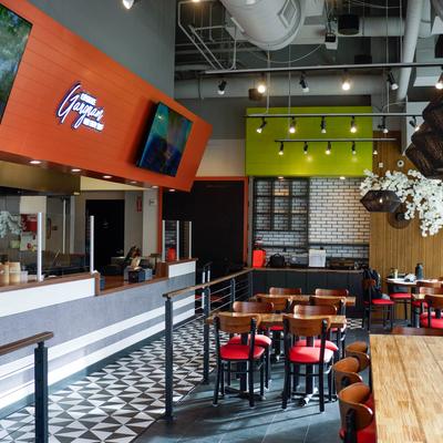 Interior with red chairs and wooden tables, a tiled floor pattern and a counter area.