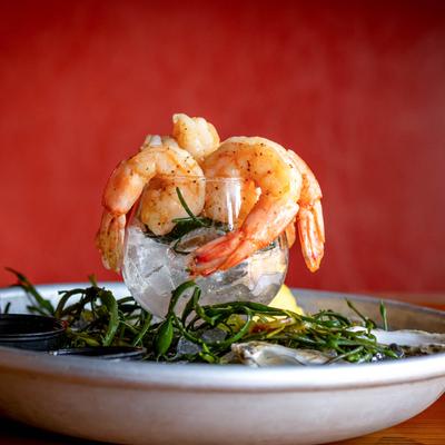 A platter of oysters and shrimp on ice, served with various dipping sauces.