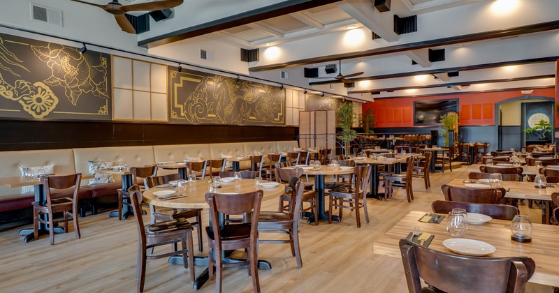 Spacious interior - wooden tables and chairs, decorative golden wall panels and ceiling fans