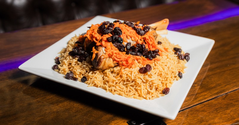 Lamb shank on a bed of rice topped with carrots and raisins