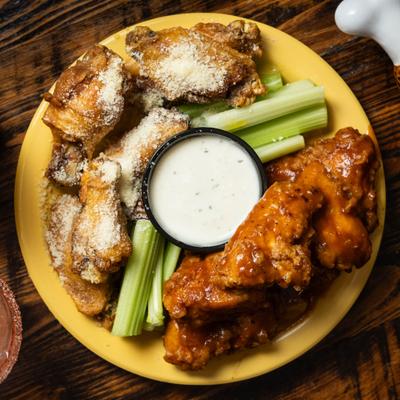 Two types of chicken wings served with celery sticks and a dipping sauce.
