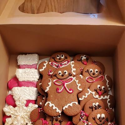 A festive box of gingerbread cookies and white and red snowflake-shaped cookies.