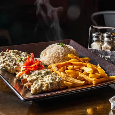 Chicken topped with gravy, served with fries and rice.