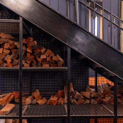 Wood logs stacked under a staircase.