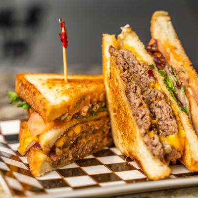 Patty Melt sliced in half and served on a checkered tray.