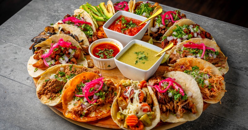 A platter of assorted tacos with various fillings and salsas