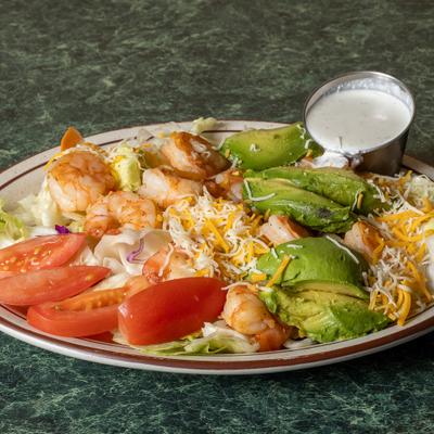 Shrimp salad with avocado, tomatoes, shredded cheese, lettuce, and creamy dressing on the side.