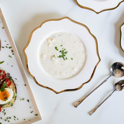 Multiple food plates with clam chowder soup plate in as the centerpiece, top view.