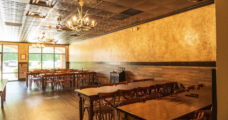 Interior featuring lots of natural light, tables, chairs, speakers and antler chandeliers