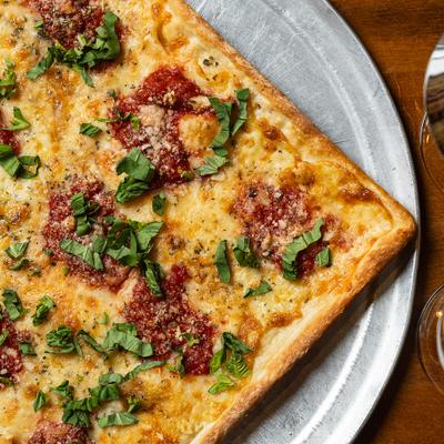 Grandmas margherita pizza topped with fresh basil, close-up.