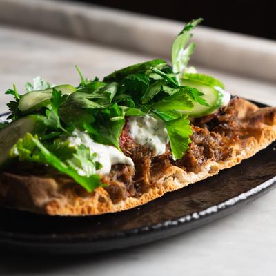 Pork  shawarma on flatbread with tomatoes, onions, tzatziki, cucumbers and parsley