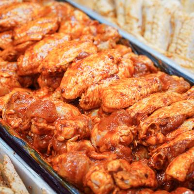 Raw, marinated chicken wings in a display case.