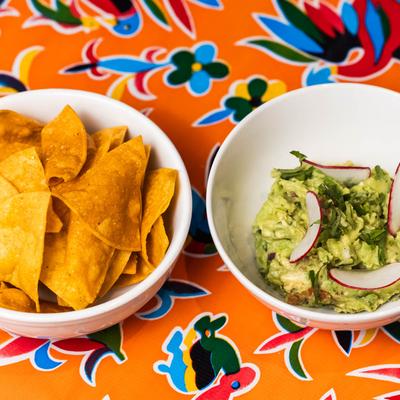 Guacamole and Chips set against a colorful patterned tablecloth.