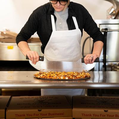 A staff member cutting pizza.