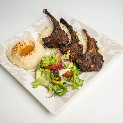 Grilled lamb chops, on a bed of rice, with hummus, and salad.