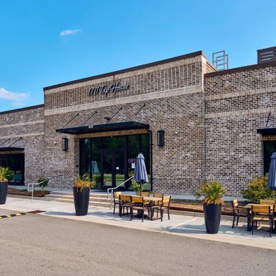 Exterior, stone brick building with entrance, signage and outdoor seating.