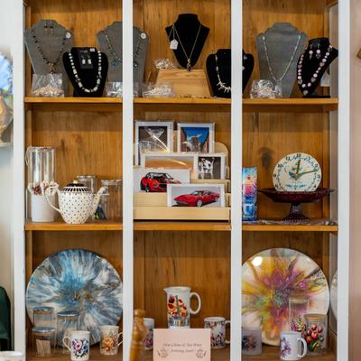 Jewelry, decorative plates, teapots, and photo frames displayed on a shelf.