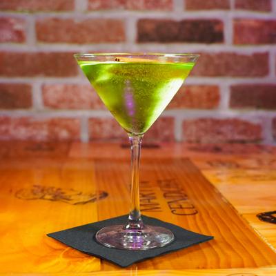 Bright green cocktail served in a martini glass on a wooden table.