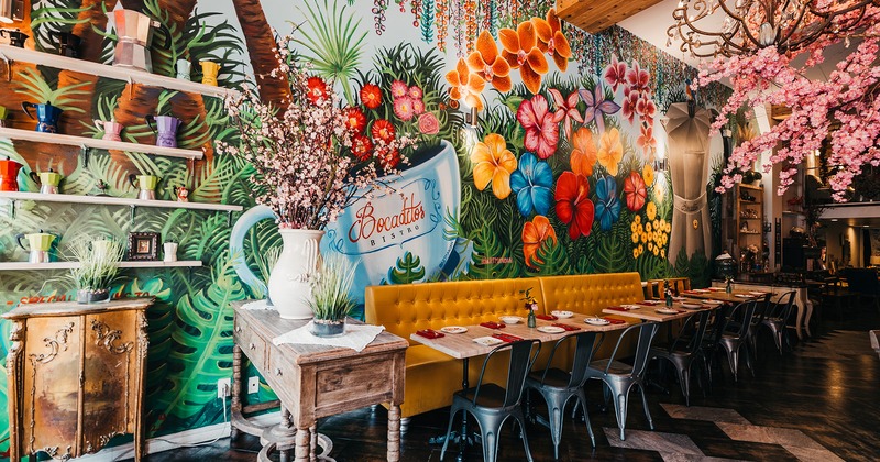 Interior space, lined up dining tables and seating, a large mural on the wall