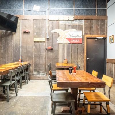 Interior, rustic seating area design with tables and chairs, and a TV on the wall.