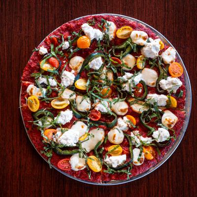 The Catania Pizza served on a metal tray on a wooden table, overhead view.