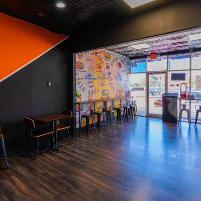 Interior featuring a distinctive orange accent wall, counter and table seating.