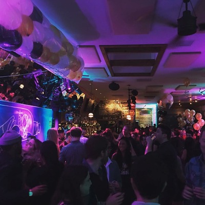 Interior with party a atmosphere, people, party lights, and balloons.