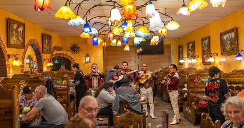 Interior, a live band playing music, customers sitting at tables, lighting, paintings