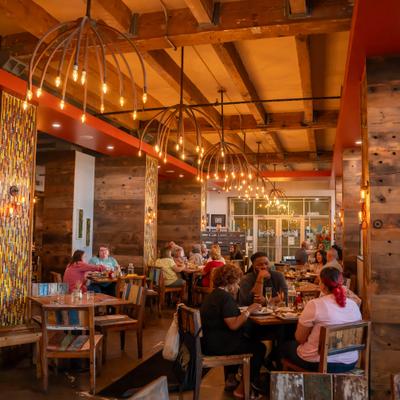 People dining in a restaurant with wooden beams and warm lighting.