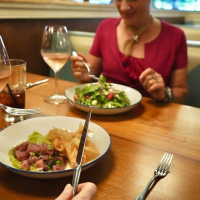 Two people enjoy their meals accompanied with glasses of rosé wine.