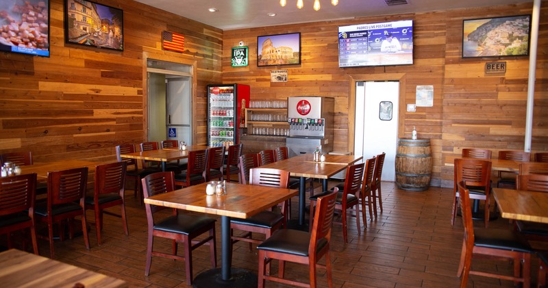 Interior, lined up tables, soda dispenser and fridge, wall TV screens