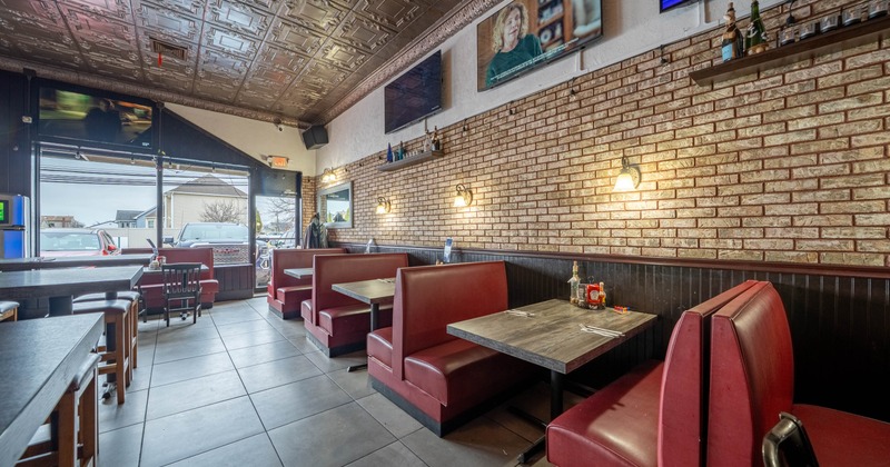 Interior with red booths, brick walls and television screens.