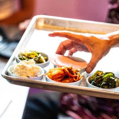 Metal tray holding a variety of small Korean side dishes.