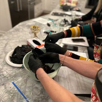 Students in aprons preparing food at a kitchen table.