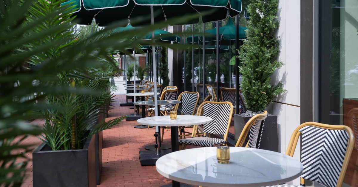Exterior, restaurant front, partially covered seating area, round tables for two under parasols